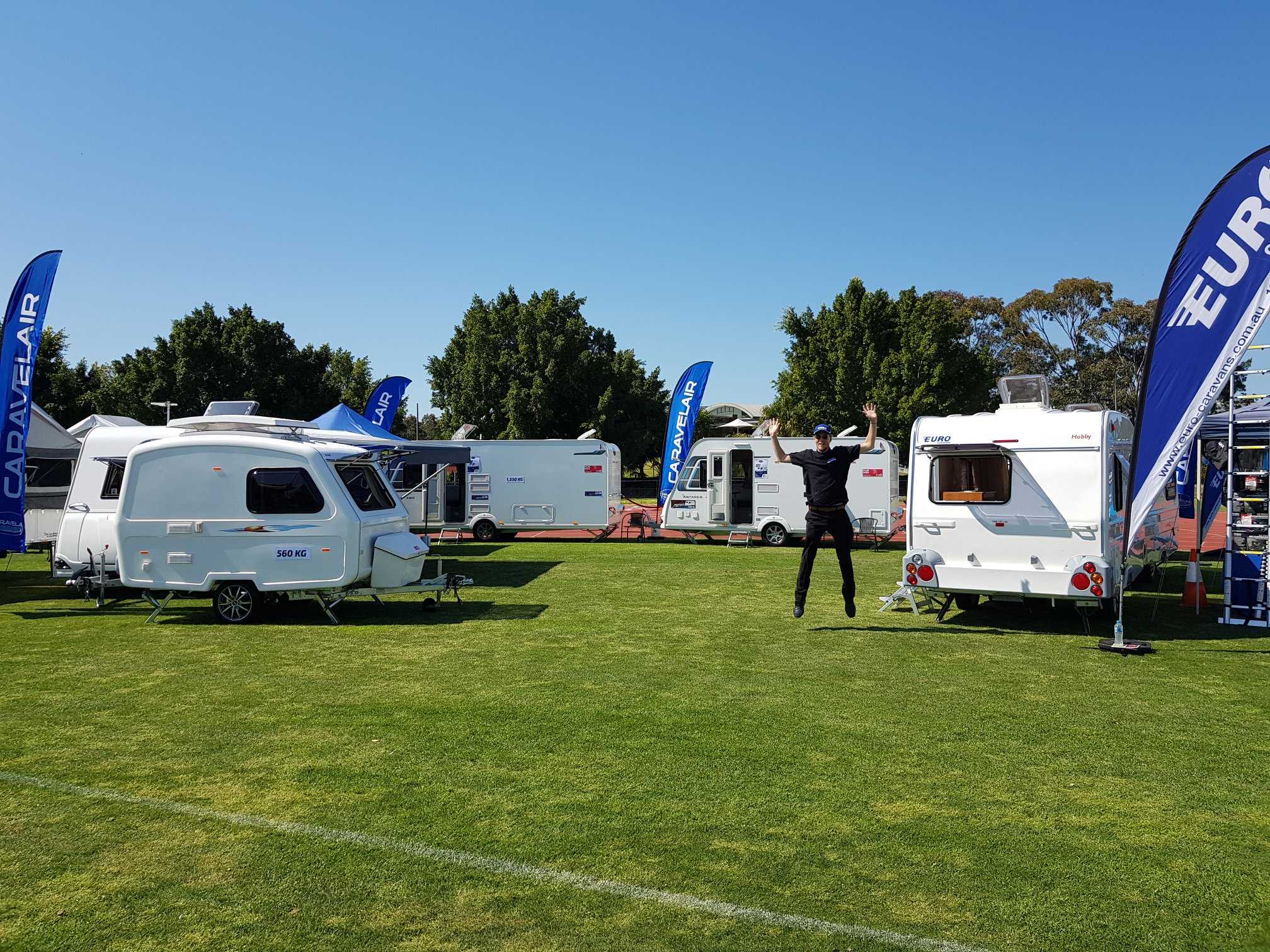 Carlight caravans at an expo on grass with man jumping in air