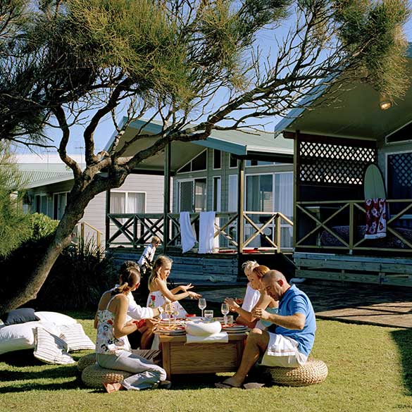 family sitting outside of cabins have lunch