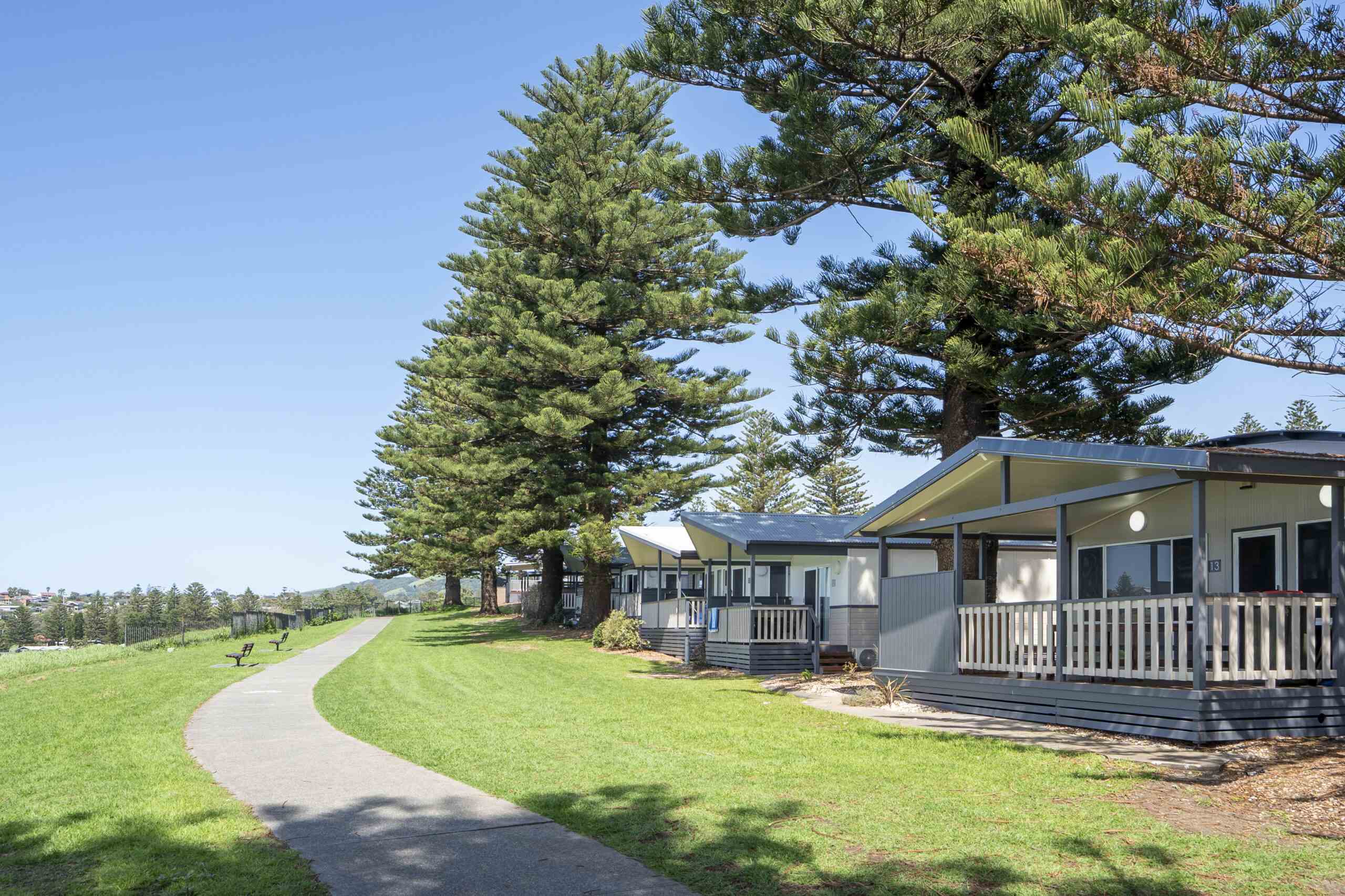 grey and white cabins with pine trees with footpath in front