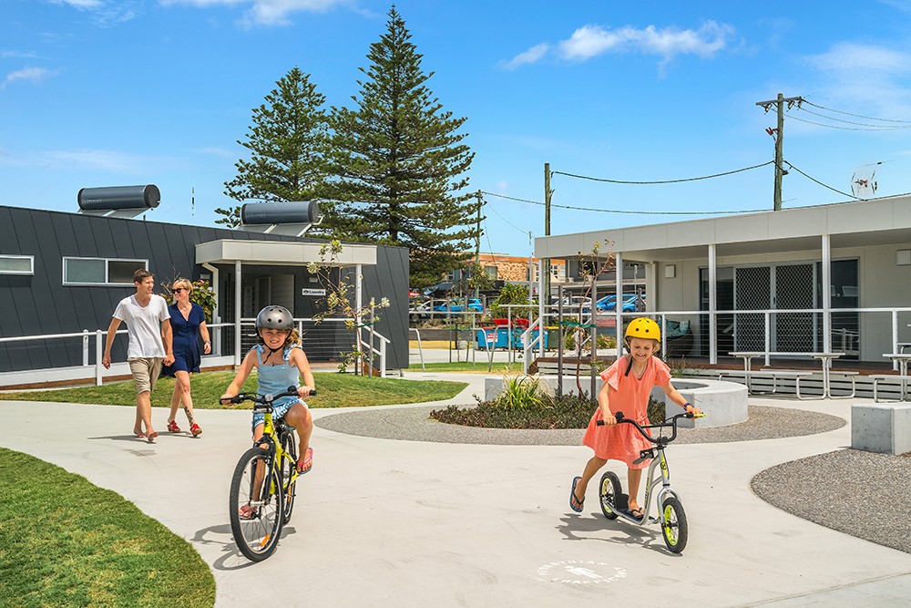 two parents walking and two children riding in park
