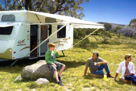 a couple with a boy sitting outside caravan with annex out