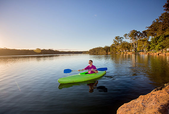 man in green kayak paddling on lake