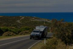 on the move caravan being towed up hill with ocean in the back ground
