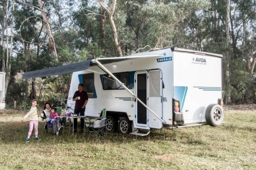 Avida Emerald caravan with awning out with family in front in field