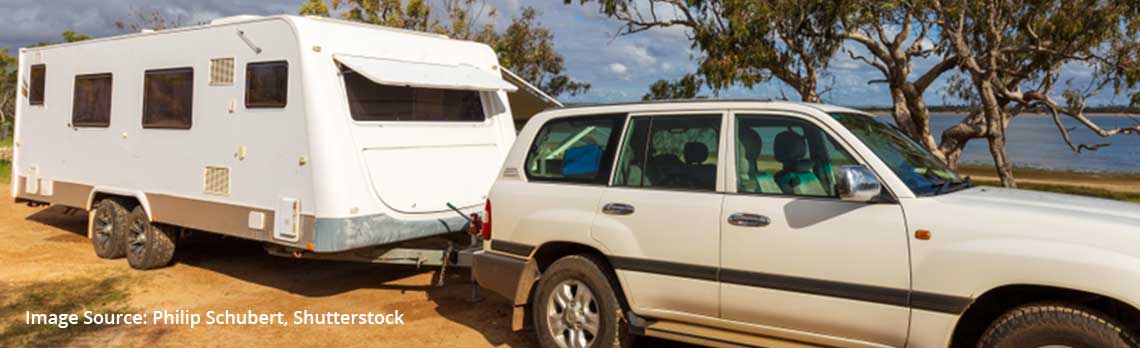 4WD and caravan parked near lake with trees