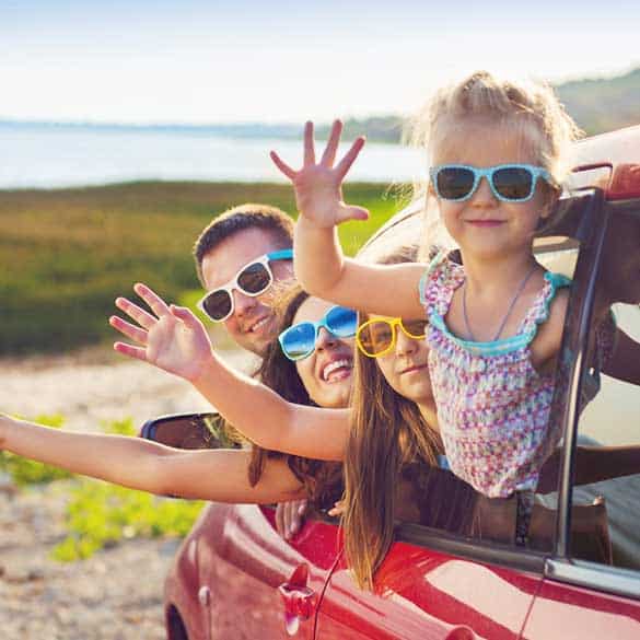 young family hanging out of car window with sun glasses on