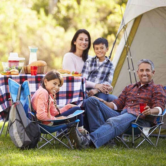 ethic family sitting round table outside tent