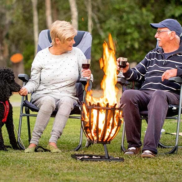 older couple sitting around fire pit with dog