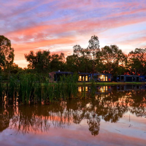 looking across water to a row of cabins and sun set in the back ground
