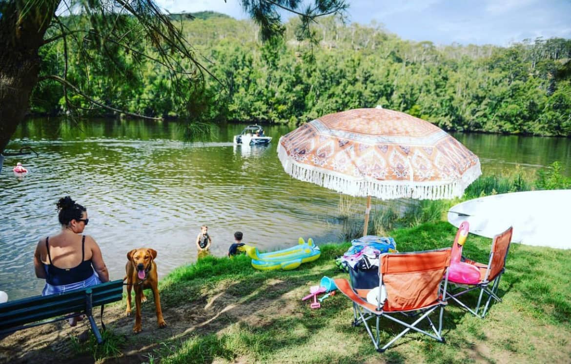 Family set up on the edge of a river with a boat going past.