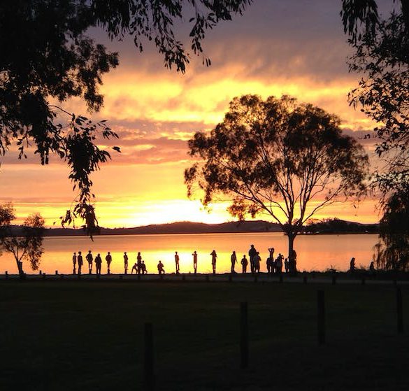 people watching sun set over lake