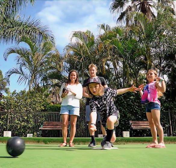 young family playing lawn bowls