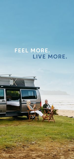 Eldering couple sitting outside of their RV on the coast