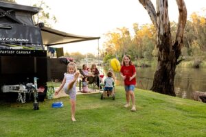BIG4 Deniliquin Holiday Park children playing near caravan on waters edge