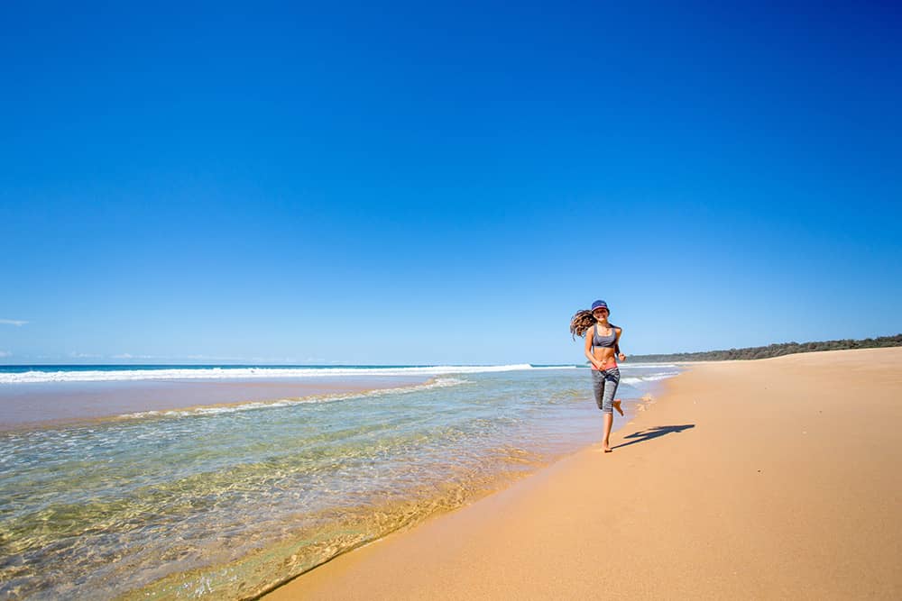 Girl jogging on a beach on a sunny day.