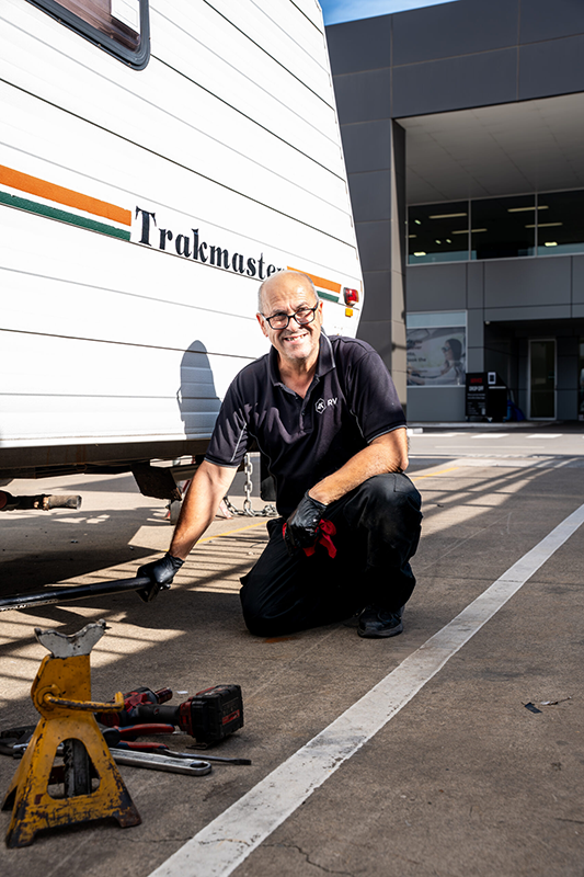 Repairer knelling down beside a caravan at 4K RV.