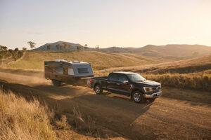 Four wheeled drive towing a caravan on a dirt road through a field in New South Wales.