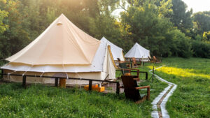 Glamping, few tents, chairs and pathway on the foreground, geenery around