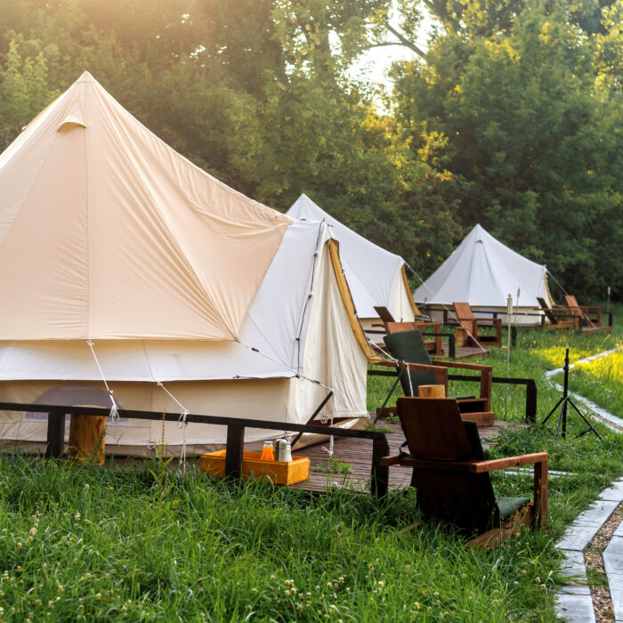 Glamping, few tents, chairs and pathway on the foreground, geenery around